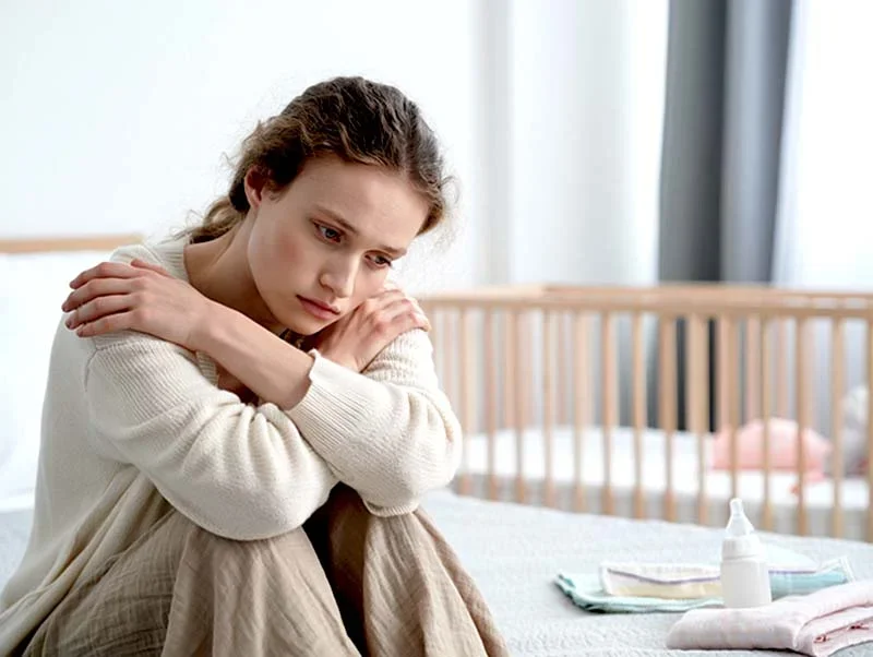 Девушка сидит возле детской кроватки